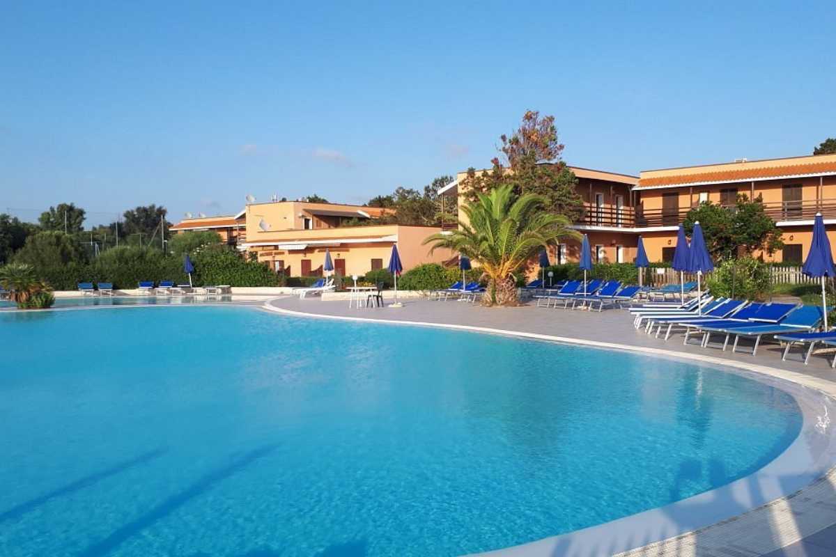 Scatto interno di un tipico appartamento vacanza a Stintino, arredi semplici, terrazza con vista mare, ciotola per cani in evidenza, luce naturale